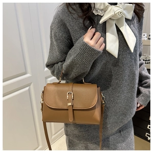 Brown lychee leather handbag featuring a gold buckle and adjustable strap shown on model