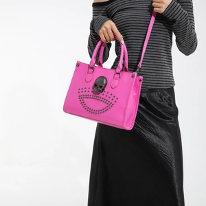 Pink punk tote bag with large skull ornament and metal rivets, worn as a shoulder bag
