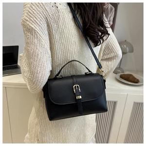 Rear view of a black lychee texture leather shoulder bag worn by a model in a modern home