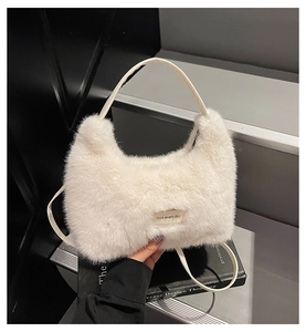 Close-up of a white plush faux fur handbag featuring a leather patch with text and a thin strap