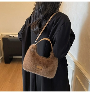 Brown faux fur crescent bag shown with adjustable leather strap and gold logo detail