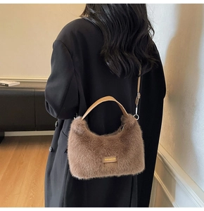Brown faux fur plush tote bag with leather tag detail shown on a model in a modern interior