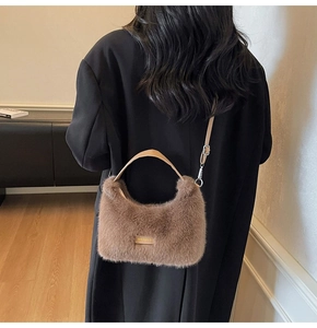 Close-up of brown faux fur shoulder bag featuring leather handles and adjustable strap detail