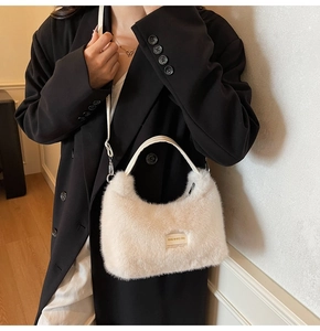 Close-up of beige plush faux fur handbag with white handles on a black blazer