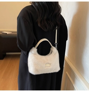 Detail of white faux fur crescent bag with love every day tag worn on a black coat