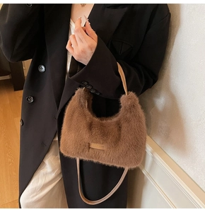 Detailed close-up of brown plush handbag with leather Love Everybody label and handle