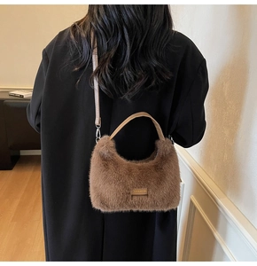 Detailed view of brown plush texture and central logo tag on the large crossbody handbag