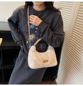 Fashionable beige plush shoulder bag with brown leather strap worn by a model in casual style