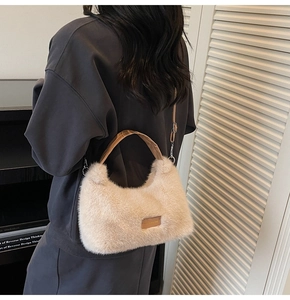 Detail of plush beige shoulder bag with leather strap and decorative nice everyday label
