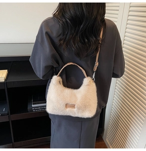 Detailed close-up of beige plush faux fur handbag with a leather strap and love tag