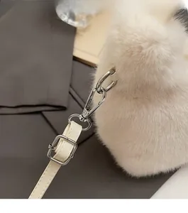 Close-up of premium silver buckle and soft faux fur texture on a cream shoulder bag