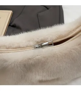 Detail of a smooth silver zipper head on a soft cream plush faux fur shoulder bag