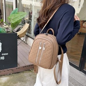 Brown faux leather backpack with diamond grid pattern shown in an outdoor cafe setting