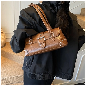 Detail view of brown vintage underarm bag with silver rivets and polished leather texture