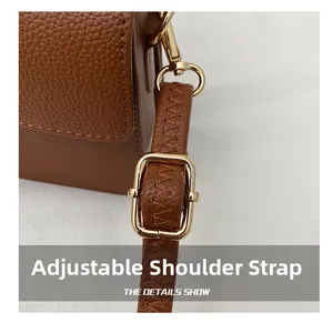 Detail of adjustable brown pebble leather shoulder strap with gold metal buckle