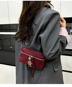 Detail of burgundy faux suede bag featuring a unique robot metal charm and zipper