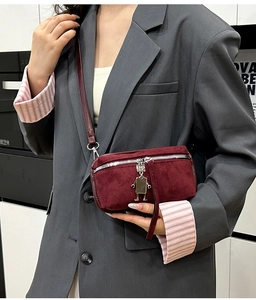 Close-up of burgundy suede crossbody bag with silver robot charm and zipper detail