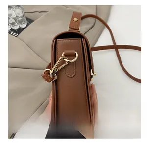 Detailed macro view of the premium golden metal hook on the brown leather crossbody bag