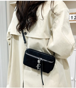 Vintage black suede crossbody bag with robot pendant shown on a beige trench coat
