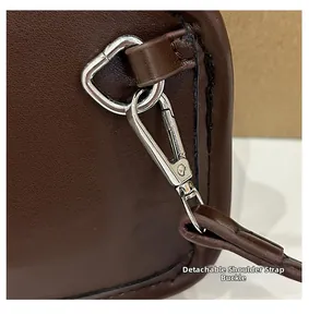 Détail du crochet en métal argenté et de la bandoulière amovible du sac en cuir