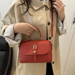 Red lychee grain leather crossbody bag for women styled with a beige trench coat