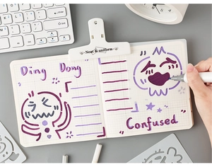 Close-up of hollow drawing templates with cute emoji patterns and grid notebook