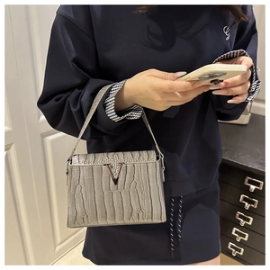 Close-up of grey crocodile texture handbag featuring a stylish silver V-shaped metal buckle