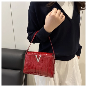 Detailed view of red crocodile pattern leather bag featuring a silver metal V-shaped buckle