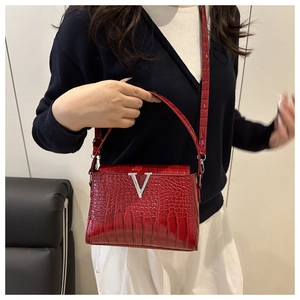 Detail of red crocodile texture handbag with V-shaped buckle and long shoulder strap