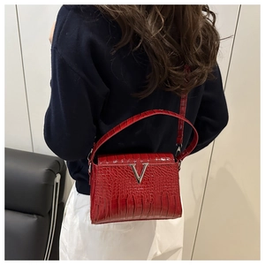Detail of red crocodile texture handbag with silver V-shaped metal buckle on side