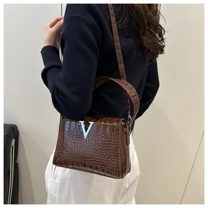 Detail of a brown crocodile leather shoulder bag featuring a silver metal V-shaped buckle