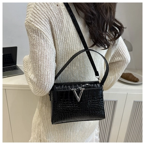 Detail of black faux crocodile leather crossbody bag with V-shaped metal hardware buckle