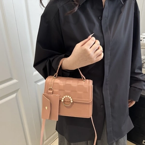 Detail of pink crossbody bag with checkered texture and elegant pearl buckle decor
