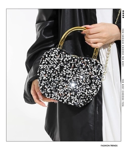 Macro shot of silver sequins and golden ring handle on a heart-shaped evening clutch bag