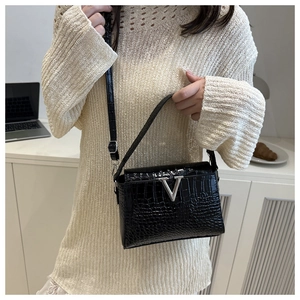 Detailed shot of black crocodile embossed crossbody bag with silver V-shaped buckle