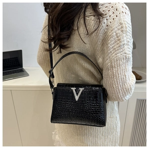Detail of a black croc-effect small square bag with a silver V metal logo shown on model