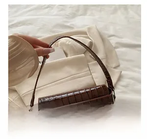 Detail of dark brown faux crocodile leather handbag with silver V-shaped metal buckle