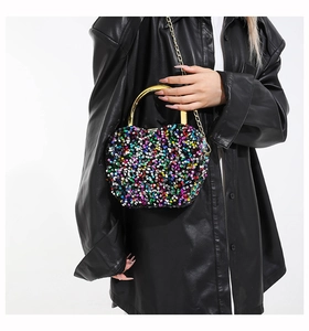 Detailed close-up of a colorful sequin handbag with a polished gold metal handle
