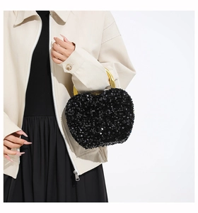 Close-up of heart-shaped black sequin handbag with luxury gold metal handle