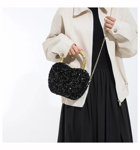 Close-up of black sequin heart handbag featuring a distinctive gold sardine metal handle