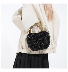 Detail of apple-shaped black sequin handbag with gold metal handle and chain strap