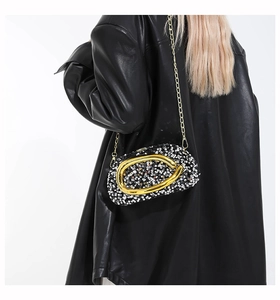Detailed side view of a black and white sequin evening clutch bag with gold chain strap