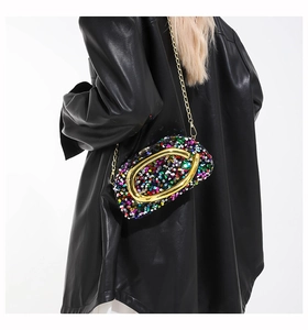 Detail of colorful sequin crossbody bag with gold metal buckle shown on a model