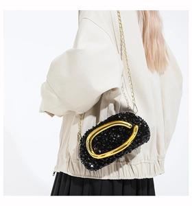 Detail of black sequin evening bag with gold metal handle and chain on shoulder