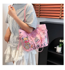 Detailed close-up of pink tote bag featuring artistic graffiti prints and a cartoon bear