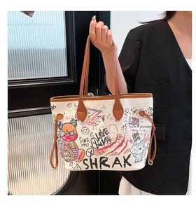 Detail of white tote bag with colorful graffiti art and brown leather handles