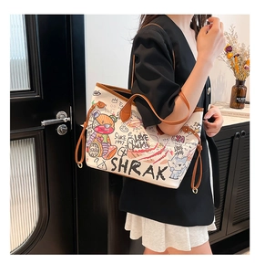 Detail of large tote bag with graffiti cartoon prints and brown leather handles