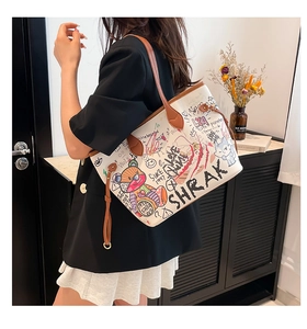Detail of white graffiti tote bag with colorful cartoon patterns and brown leather strap