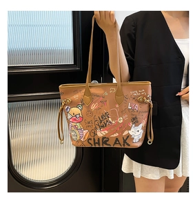 Detail of a brown tote bag featuring colorful cartoon graffiti and side drawstring accents