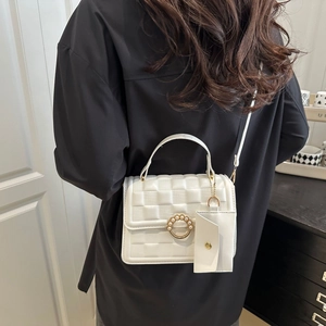 Detail of white quilted crossbody bag featuring a pearl clasp and detachable mini card pouch